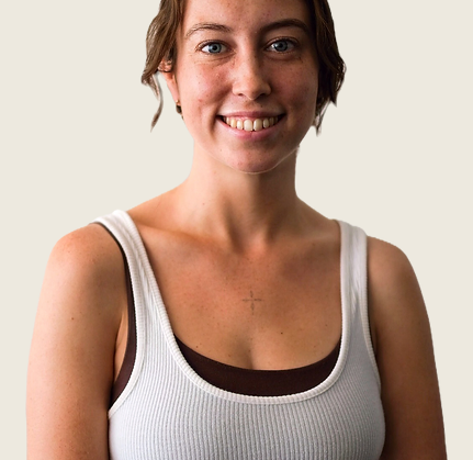 Woman smiling in white tank top.