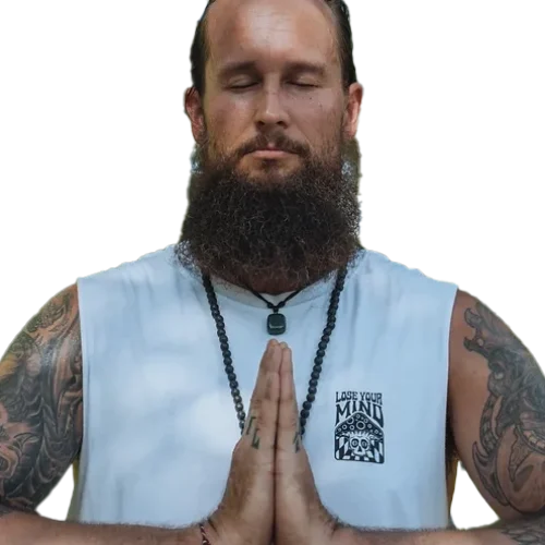 Man meditating with tattoos and a beard.